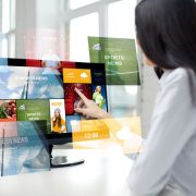 close up of woman with news on computer in office business, people, technology and mass media concept - close up of woman pointing finger to news application on computer monitor in office